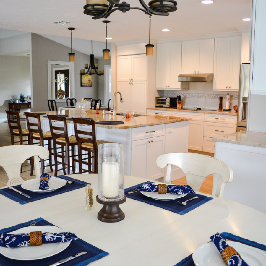 modern kitchen with white fixtures, including dining room table, chairs, cabinets, fridge