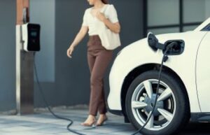 Woman Walking by a Car Using an EV Charger