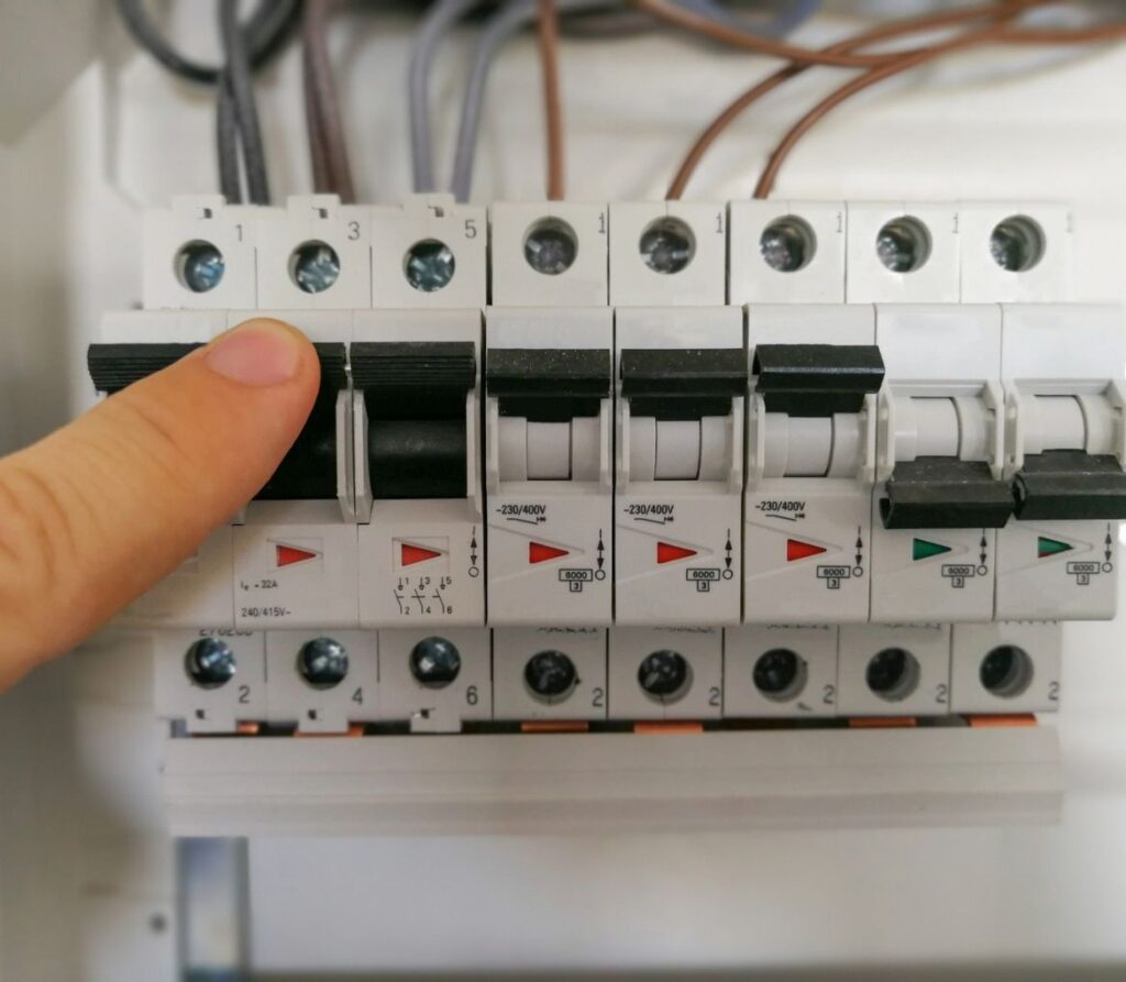 Male finger switching circuit breakers inside an electrical panel at a Palm Beach, FL residence